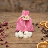 Six Beauty Scents wax melts with red pepper and greens arranged on a rustic wooden table, with a pink linen bag and brown tag in the background.