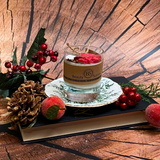 Decorative candle with holly berries and pine cones on a wooden surface