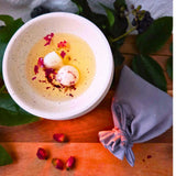Beauty Scents wax melts with rose petals, two melts melting in an oil burner next to a grey linen bag, top view, close-up.