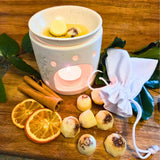 Six Beauty Scents wax melts with shredded cinnamon on a wooden table next to a white linen bag and a white oil burner melting two melts.
